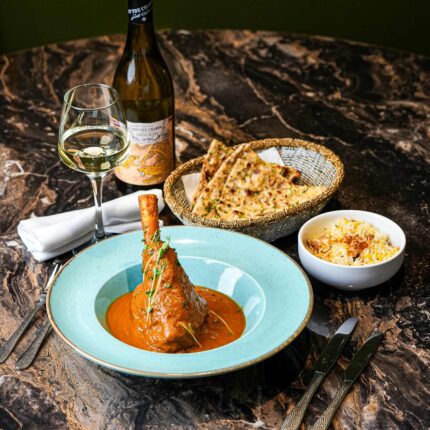 Signature Lamb Shank Sankha dish served with rice and naan on the Panas Restaurant menu.