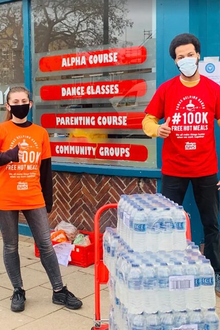 Volunteers distributing charitable food parcels in branded Panas bags to people in need.
