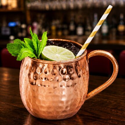 A refreshing Moscow Mule cocktail served in a traditional hammered copper mug with mint and lime.