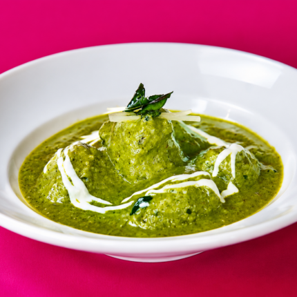 Vibrant green spinach curry drizzled with fresh cream and garnished with ginger juliennes.