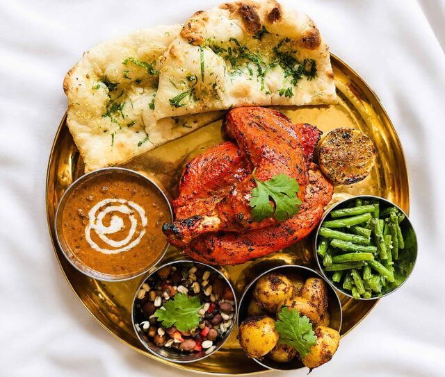 A unique Gurkha Sunday roast platter featuring Tandoori chicken, spiced potatoes, dal, and naan bread at Panas Restaurant in Blackheath.