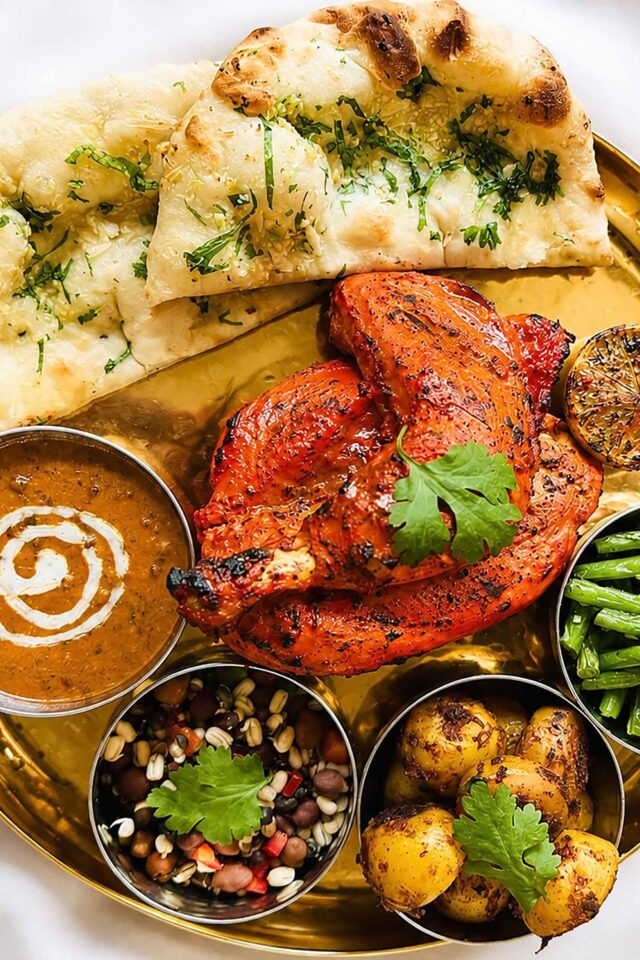 A unique Gurkha Sunday roast platter featuring Tandoori chicken, spiced potatoes, dal, and naan bread at Panas Restaurant in Blackheath.