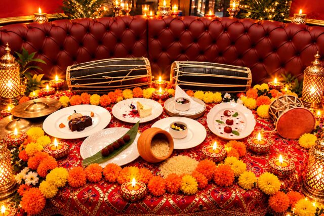 Festive Diwali dining table at Panas Restaurant featuring Indian and Nepalese desserts, lit diyas, marigold garlands, and traditional drums.
